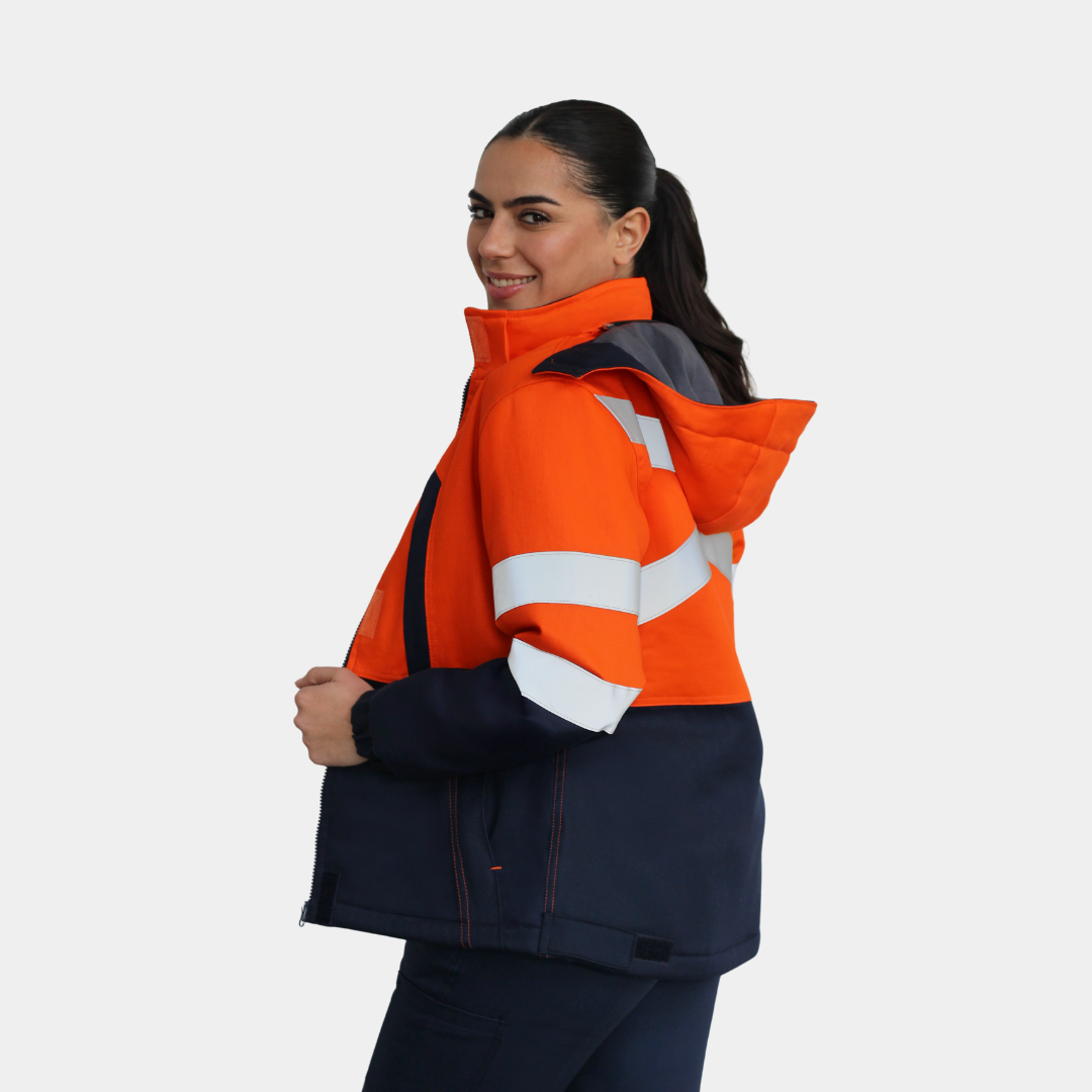 Mujer usando chaqueta térmica ignífuga FIREWEAR® bicolor naranjo y azul en vista posterior tres cuartos.